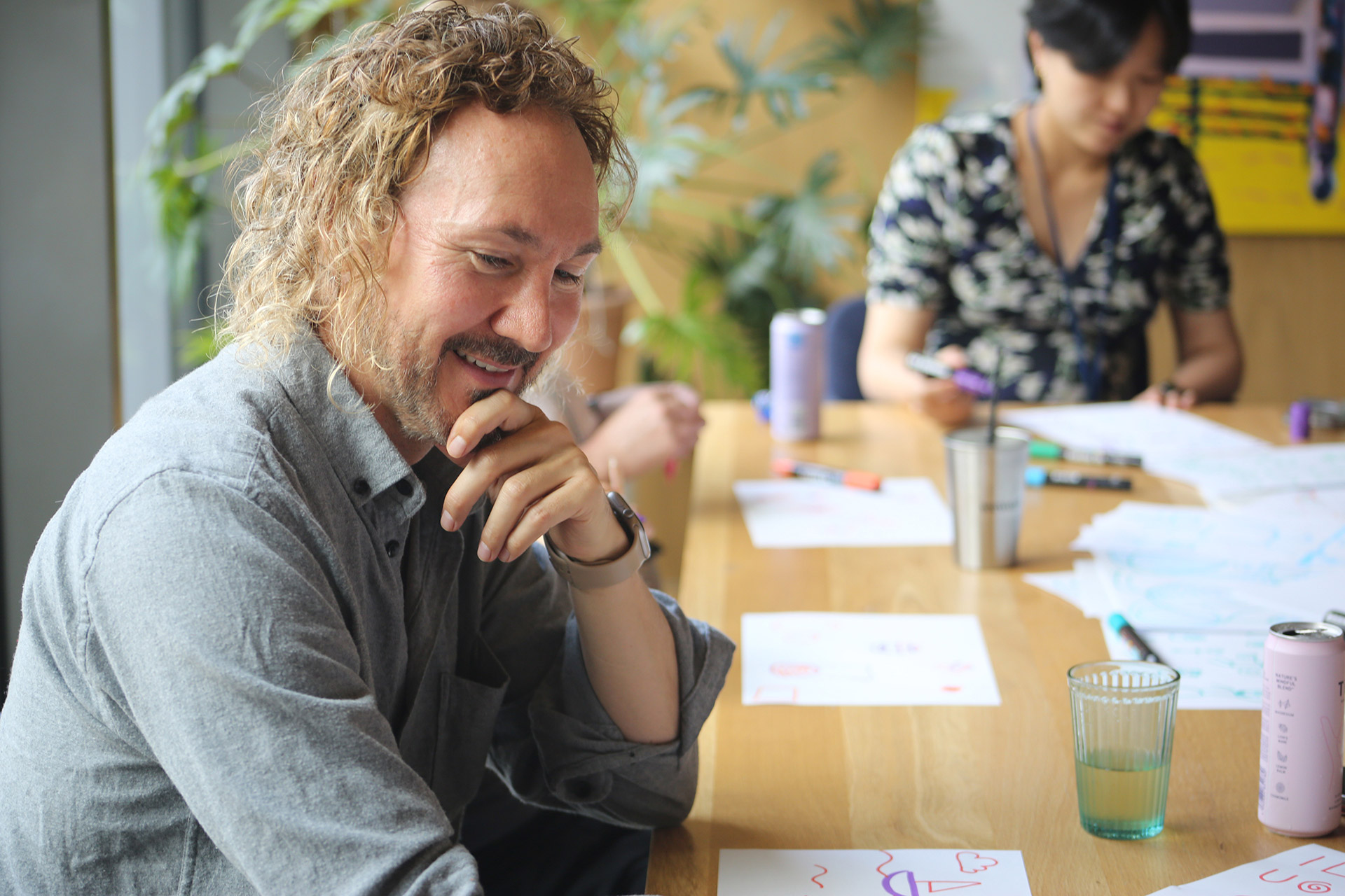 A man smiles at the doodle workshop, his hand is resting on his chin